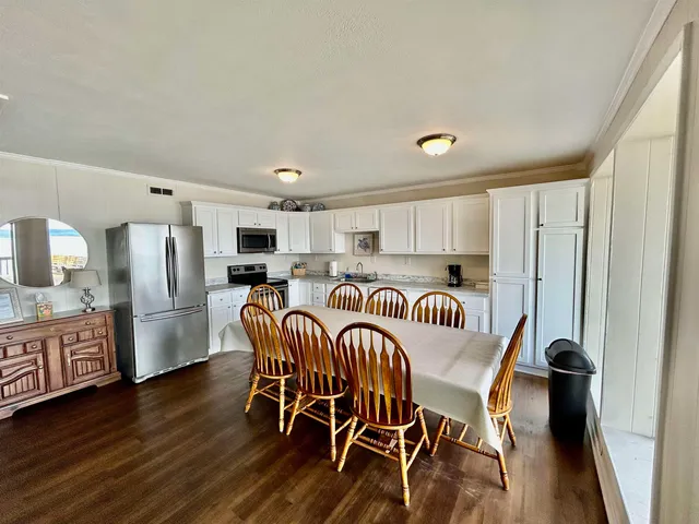 a kitchen with stainless steel appliances granite countertop a dining table chairs refrigerator and sink