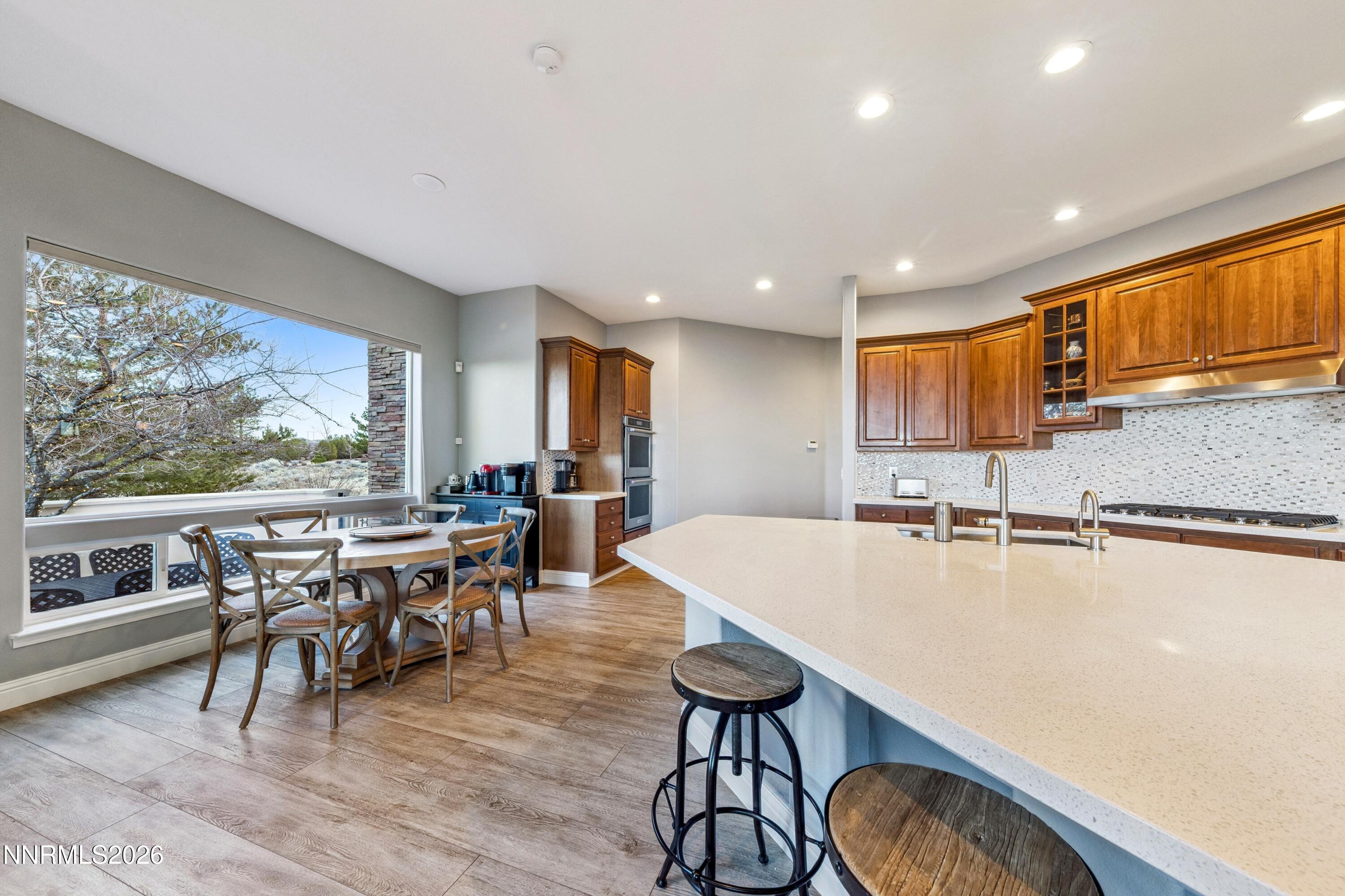 3670 Spirit Bluff Court Reno, NV 89511 - Photo 18 of 54 a open dining room with stainless steel appliances granite countertop a stove a refrigerator a kitchen island a table and chairs with wooden floor