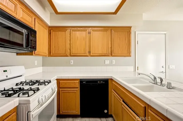 a kitchen with stainless steel appliances a stove top oven a sink a refrigerator white cabinets and wooden floor