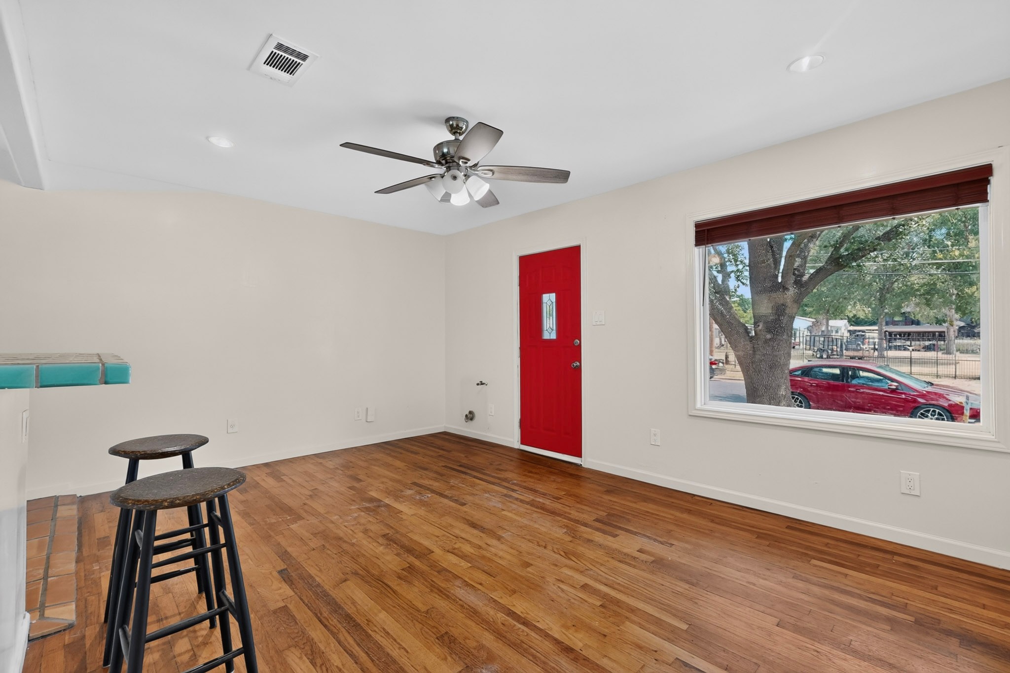 4711 Alf Avenue Austin, TX 78721 - Photo 5 of 34 Hardwood flooring extends throughout this versatile living space, anchored by a distinctive red entry door.