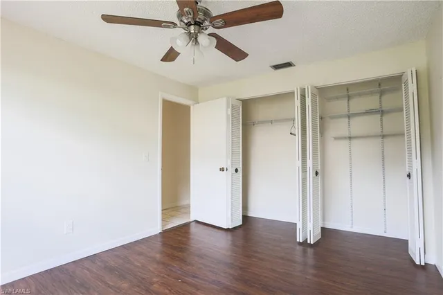 an empty room with wooden floor and ceiling fan
