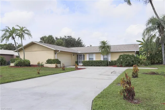 a front view of house with yard and trees in the background
