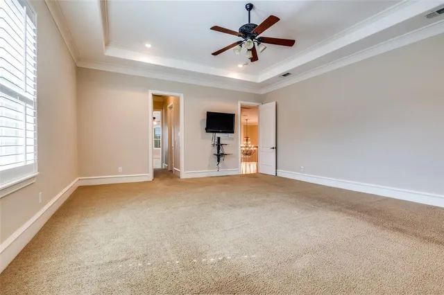 a view of an empty room with chandelier fan and windows
