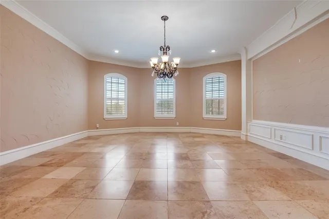 a view of an empty room with window and chandelier