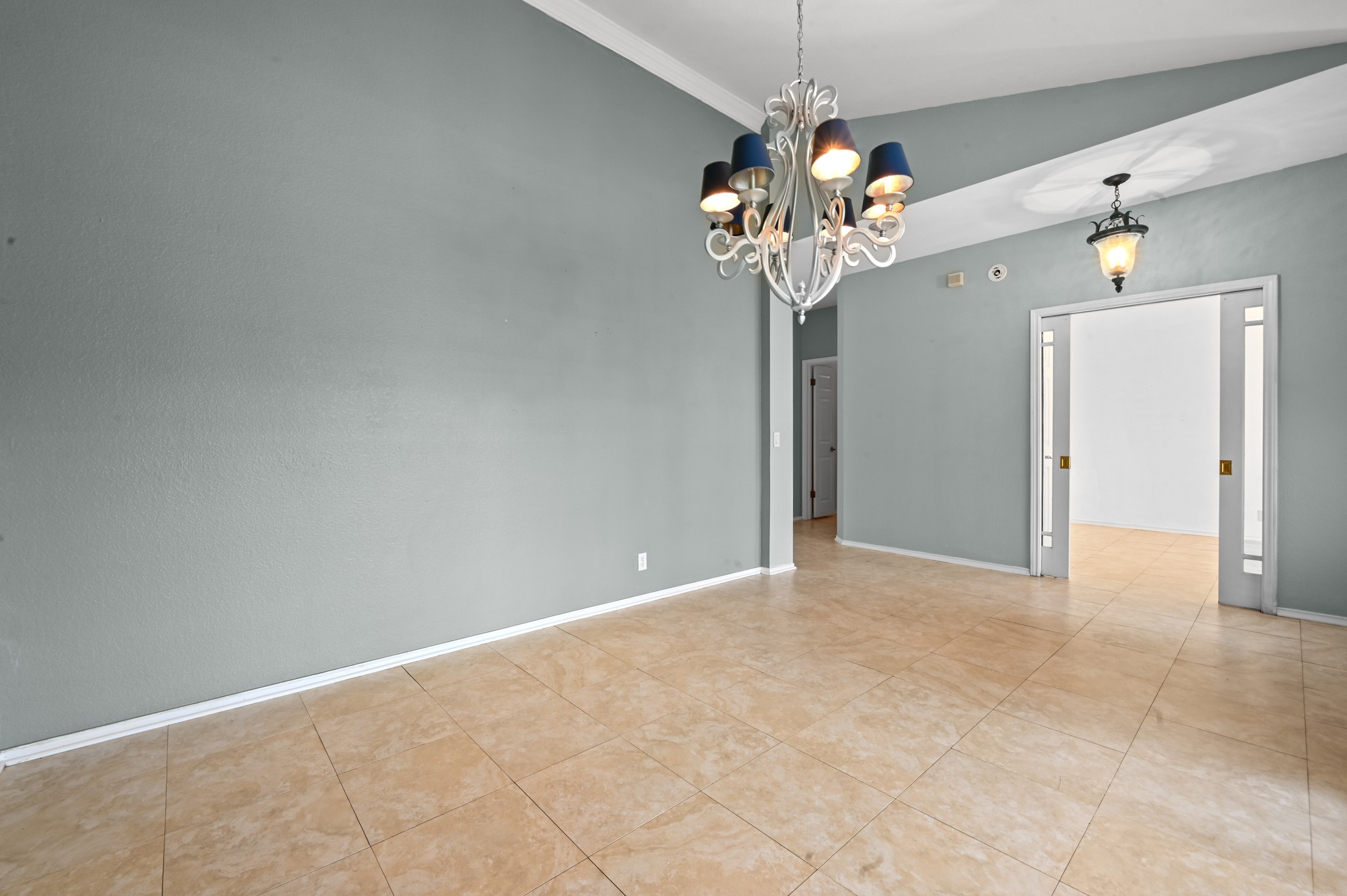 5313 Moon Shadow Drive Austin, TX 78735 - Photo 10 of 30 Spacious room featuring tile flooring, vaulted ceilings with crown molding, and a decorative chandelier