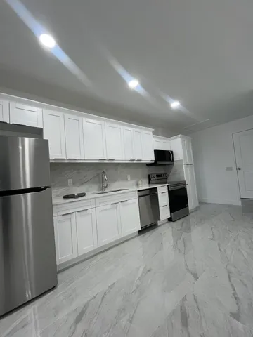 a kitchen with stainless steel appliances a refrigerator sink and white cabinets