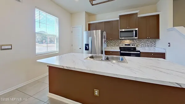 a kitchen with stainless steel appliances a sink a microwave a refrigerator and cabinets