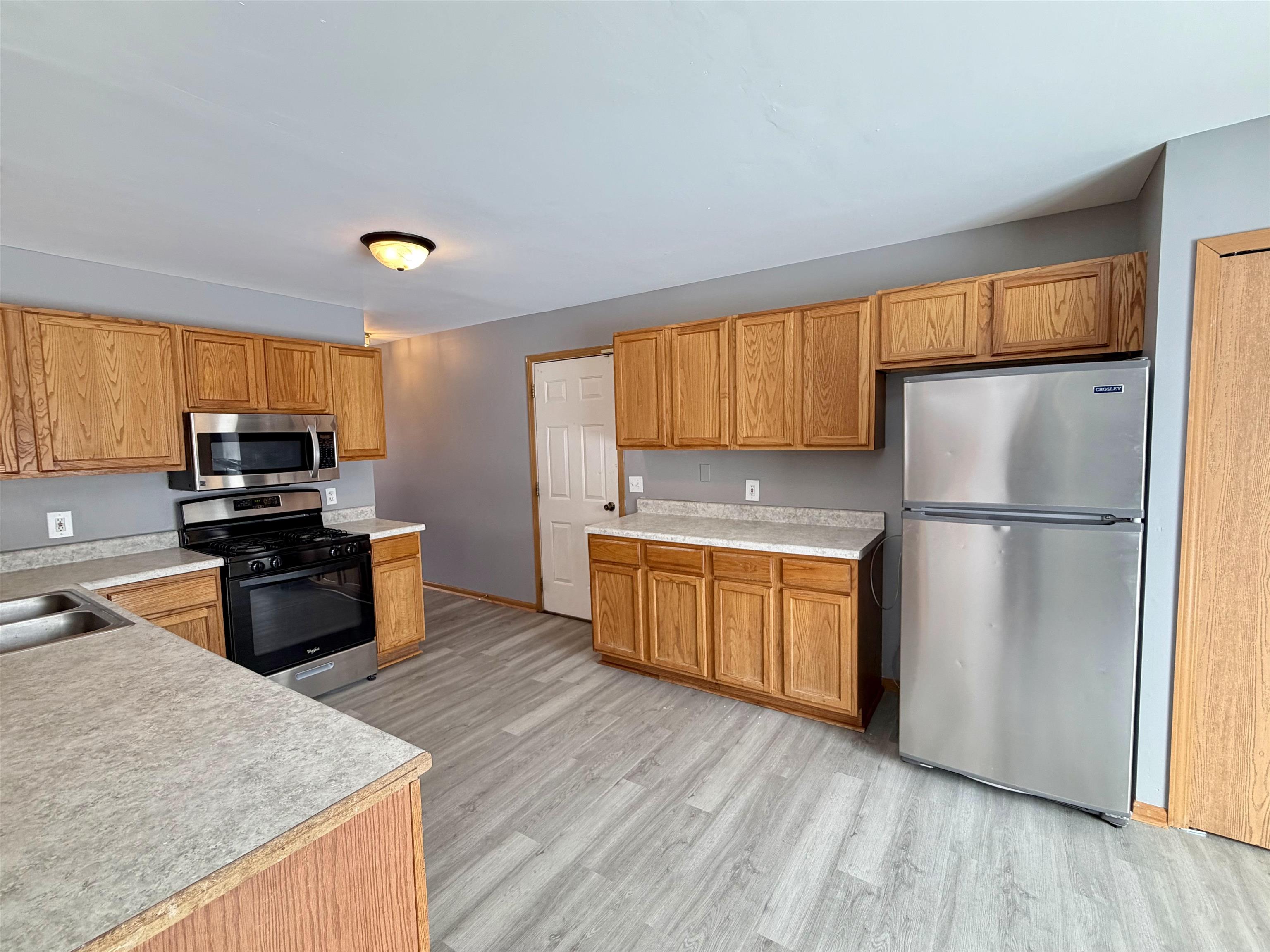 2424 Winfield Lane Belvidere, IL 61008 - Photo 6 of 30 a kitchen with wooden floors stainless steel appliances and window