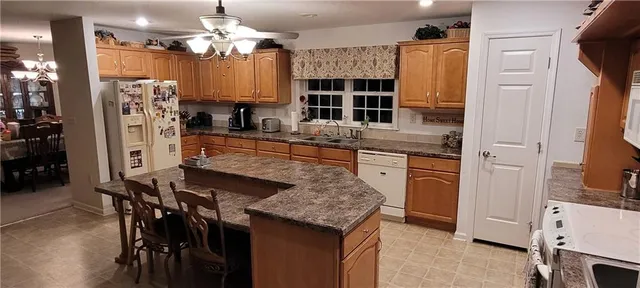 a kitchen with kitchen island granite countertop a table chairs refrigerator and cabinets