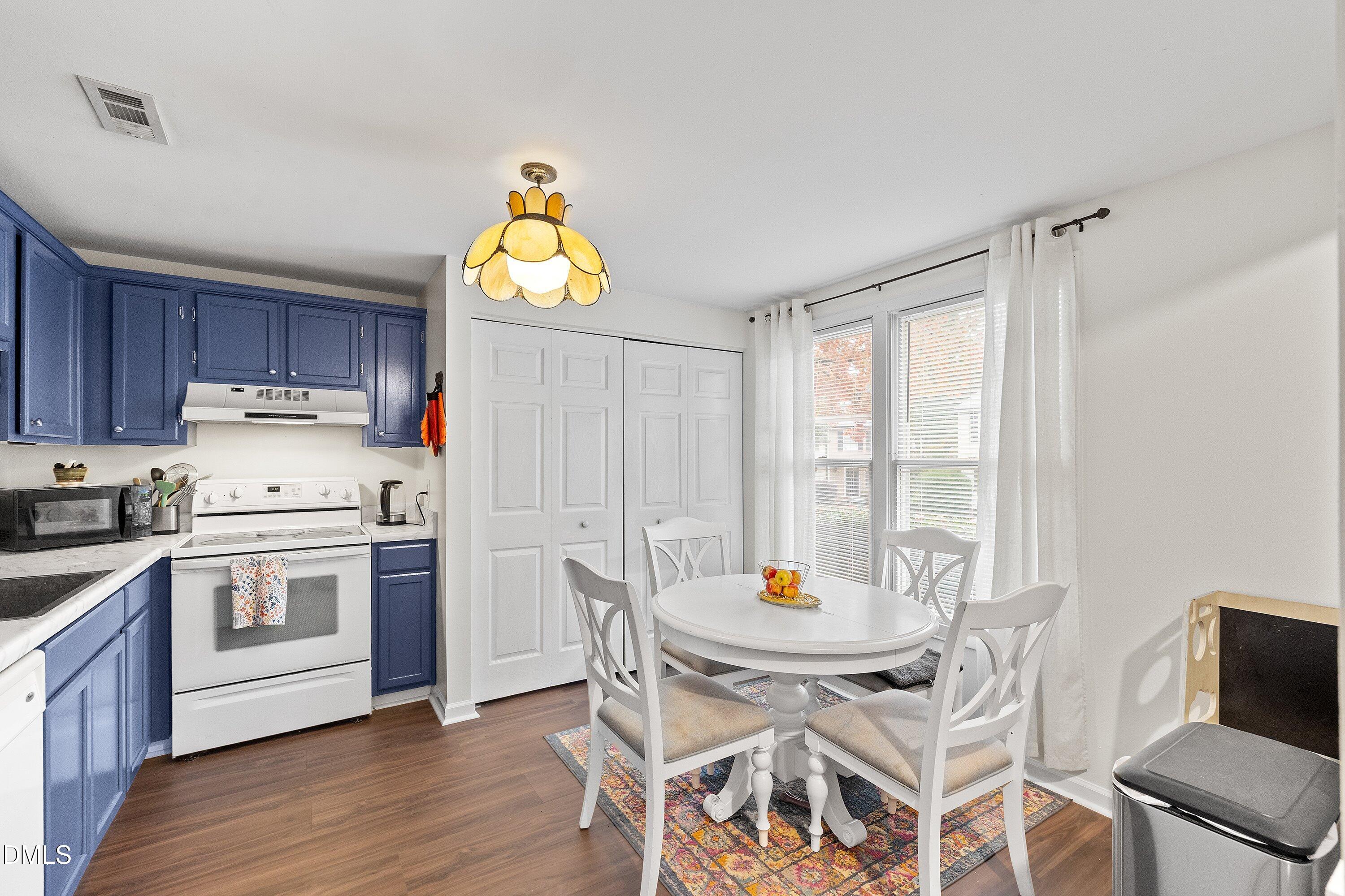 7729 Bernadette Lane Raleigh, NC 27615 - Photo 5 of 34 a kitchen with stainless steel appliances wooden floor dining table and chairs