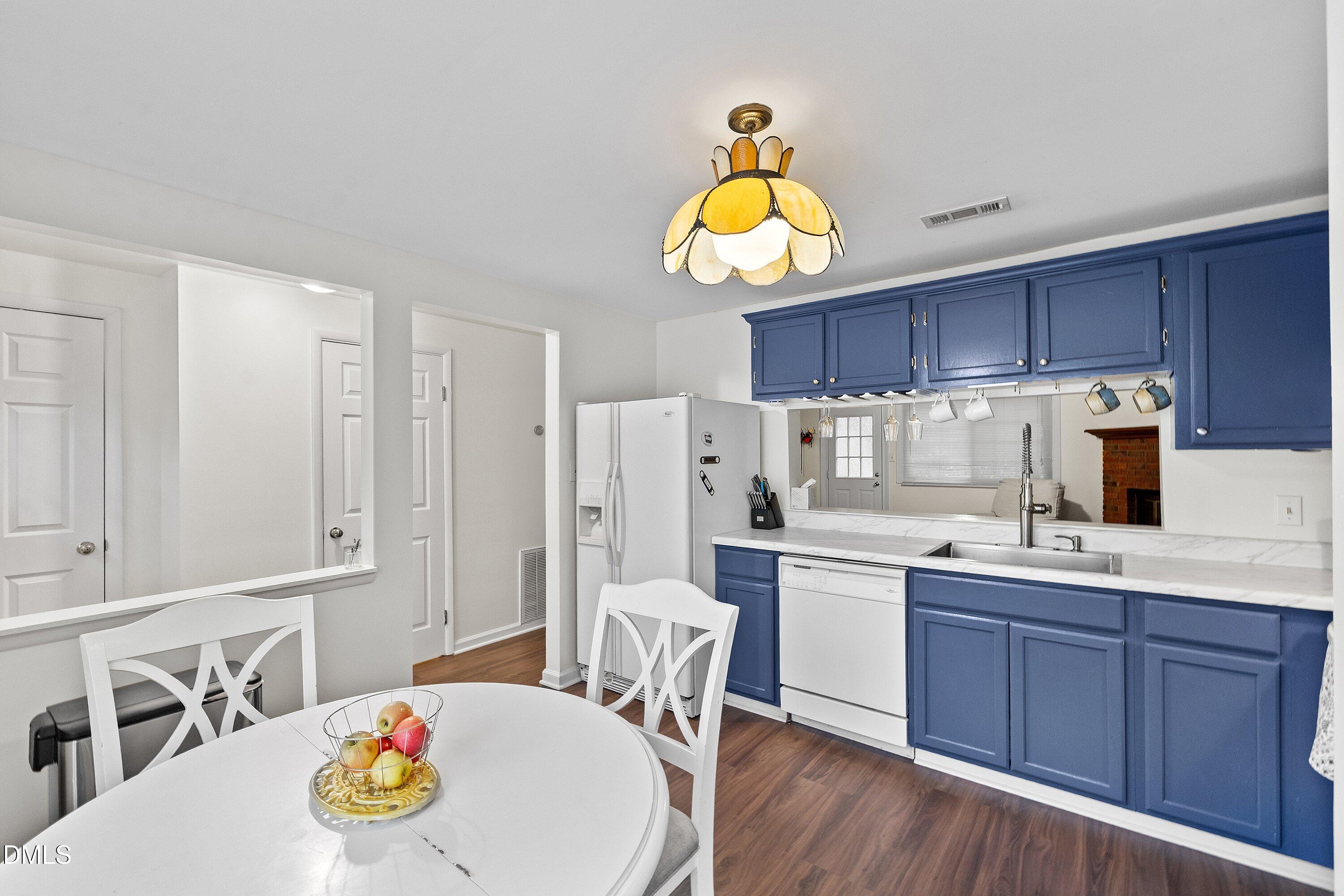 7729 Bernadette Lane Raleigh, NC 27615 - Photo 7 of 34 a kitchen with a sink a stove and chairs with wooden floor