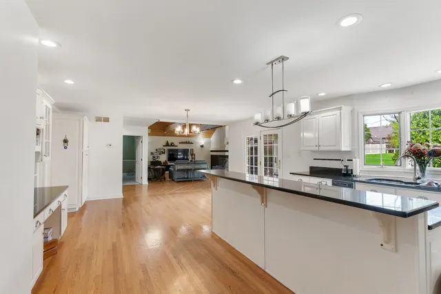 a large kitchen with stainless steel appliances a large counter top space a sink and a wooden floor