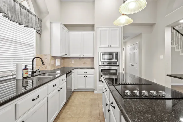a kitchen with stainless steel appliances granite countertop a sink stove and cabinets