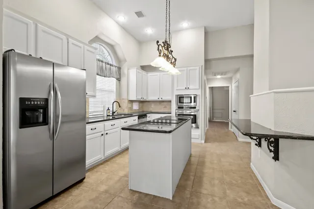 a kitchen with stainless steel appliances granite countertop a refrigerator a sink and a stove