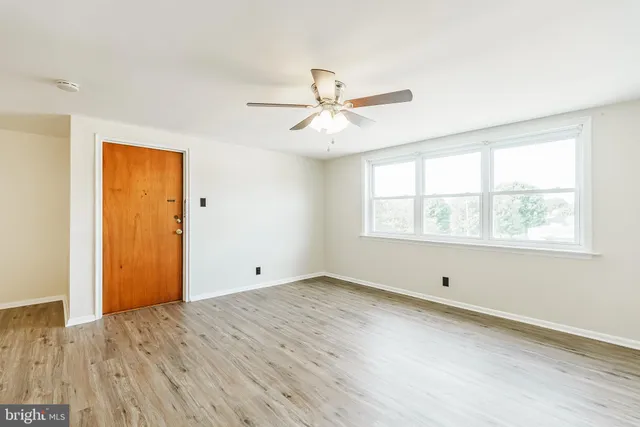 an empty room with a window and a ceiling fan
