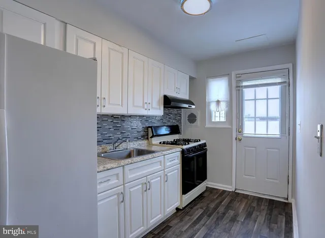 a view of a room with wooden floor staircase and a kitchen space