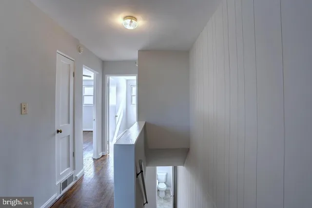a view of a hallway with wooden floor and staircase