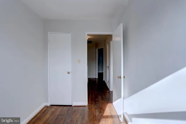 a view of a hallway with wooden floor and closet