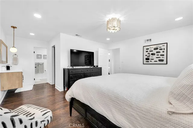 a spacious bedroom with a bed and a flat screen tv