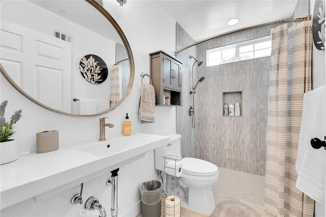 a bathroom with a sink a mirror a toilet and shower