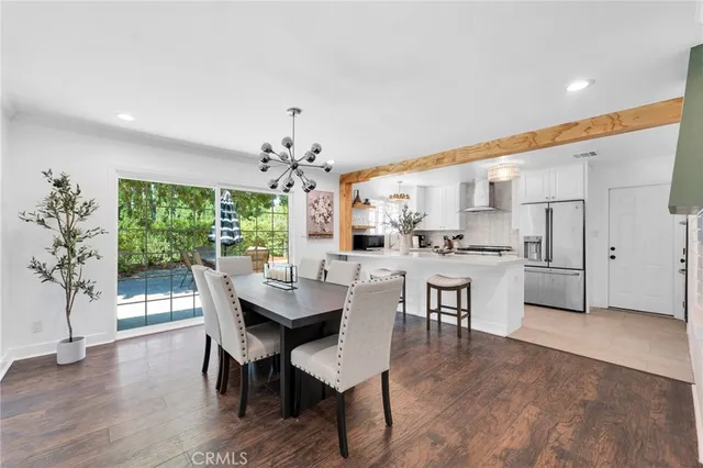 a dining room with wooden floor a chandelier a wooden table and chairs