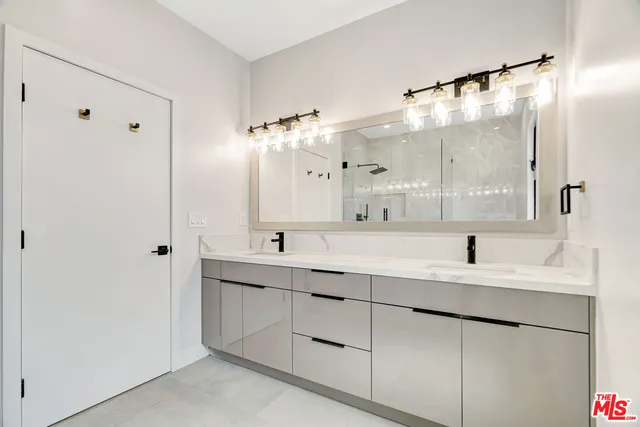 a bathroom with a double vanity sink mirror and shower