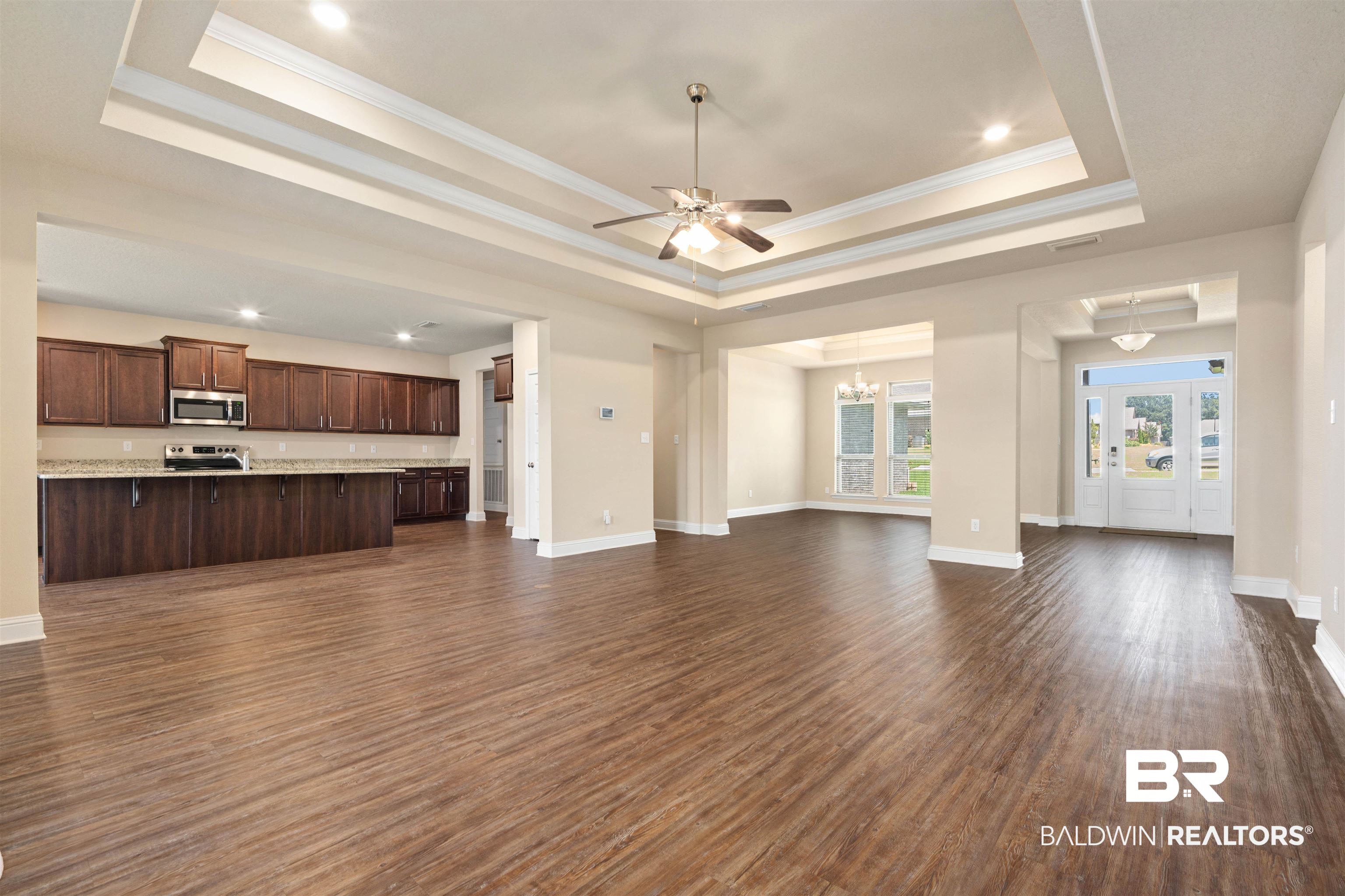 1864 Gwin Court Mobile, AL 36695 - Photo 9 of 37 Unfurnished living room featuring a raised ceiling, ceiling fan with notable chandelier, dark wood-type flooring, and crown molding