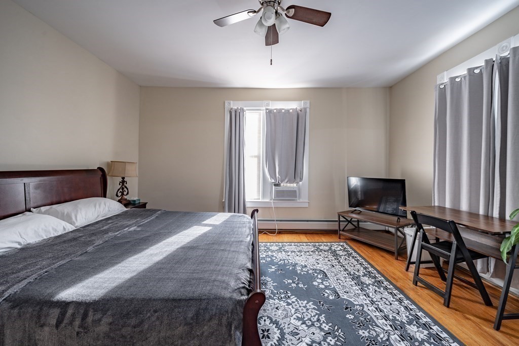 175 Mill Street Springfield, MA 01108 - Photo 24 of 42 a bedroom with a bed flat screen tv and a chandelier