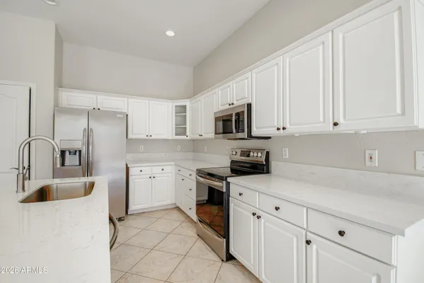a kitchen with stainless steel appliances a sink a stove a refrigerator a center island and cabinets