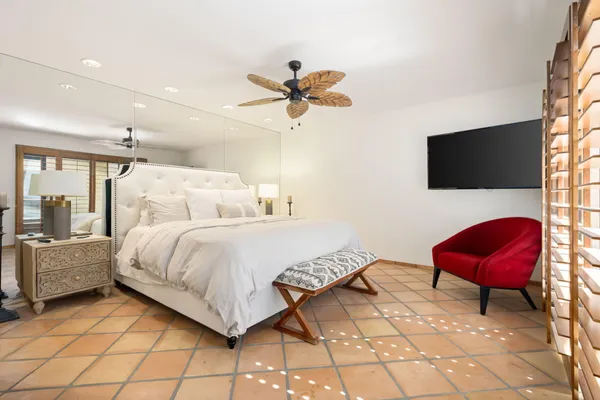 a bedroom with a bed a chair a computers on the table and a flat screen tv