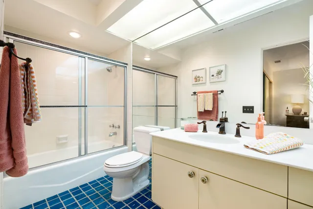 a bathroom with a double vanity sink toilet mirror and shower