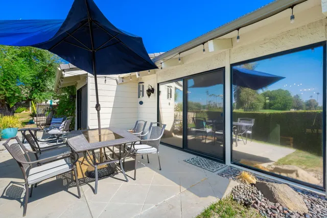 a patio with glass top table and chairs