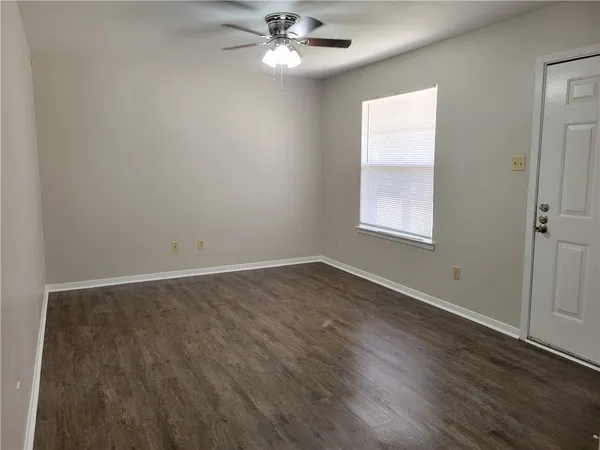 an empty room with wooden floor fan and windows