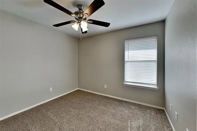 an empty room with a chandelier fan and windows