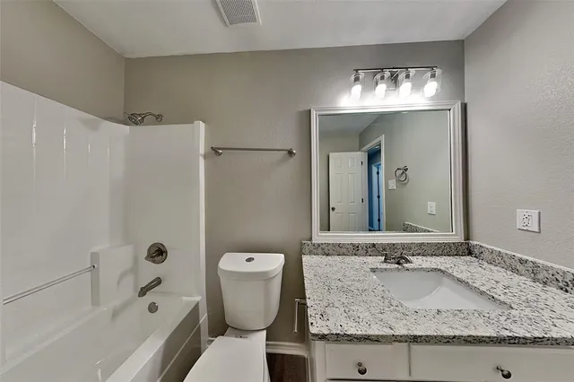a bathroom with a granite countertop sink a toilet and shower