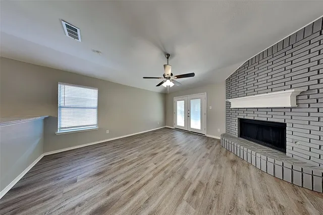 an empty room with wooden floor fireplace and window
