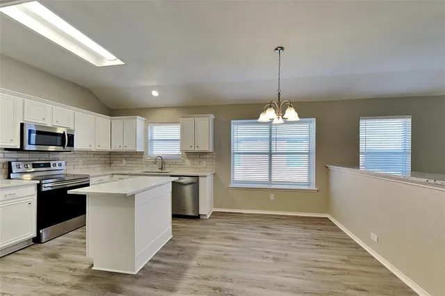 a kitchen with stainless steel appliances granite countertop a sink a stove a refrigerator and a microwave