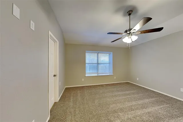an empty room with a window and a fan