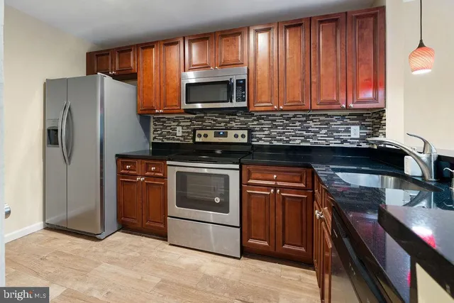 a kitchen with granite countertop a sink stainless steel appliances and cabinets