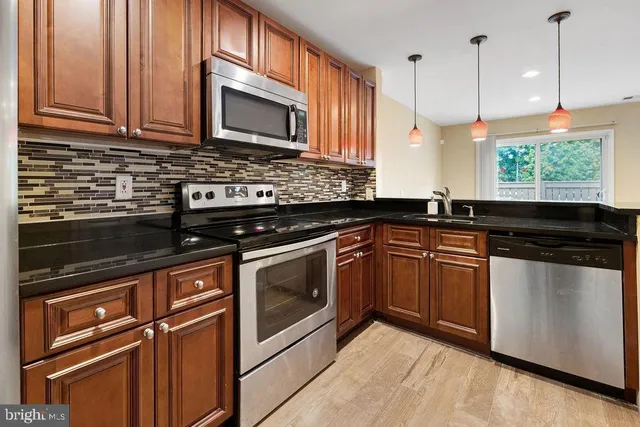 a kitchen with stainless steel appliances granite countertop a stove a sink and a refrigerator