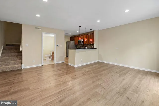 a view of a kitchen with kitchen island a sink wooden floor and a large window