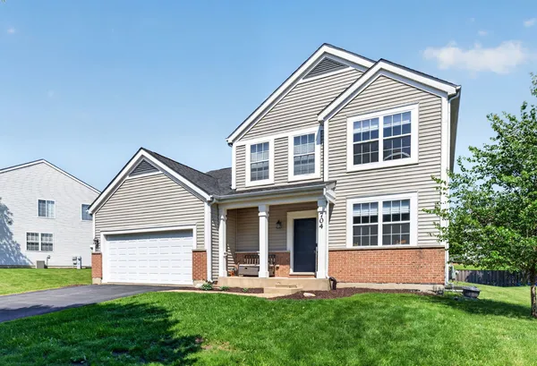 a front view of a house with a yard and green space