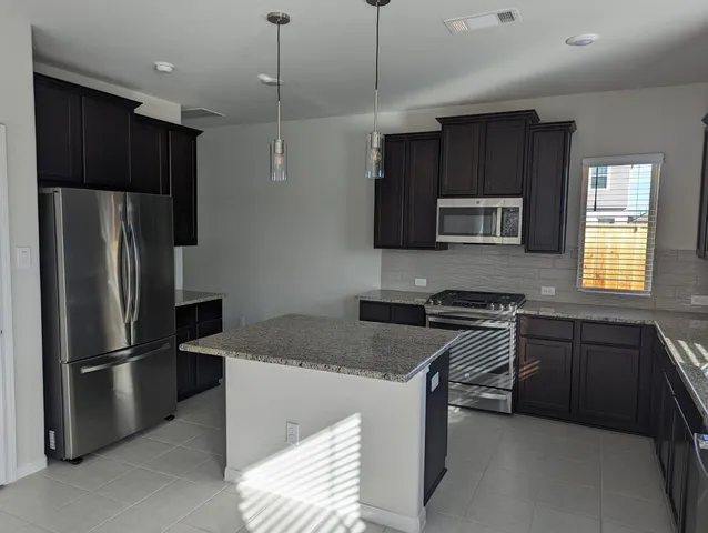 a kitchen with kitchen island granite countertop a sink stainless steel appliances and cabinets