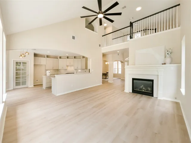 a view of a livingroom with a fireplace a ceiling fan a kitchen a sink and a large window