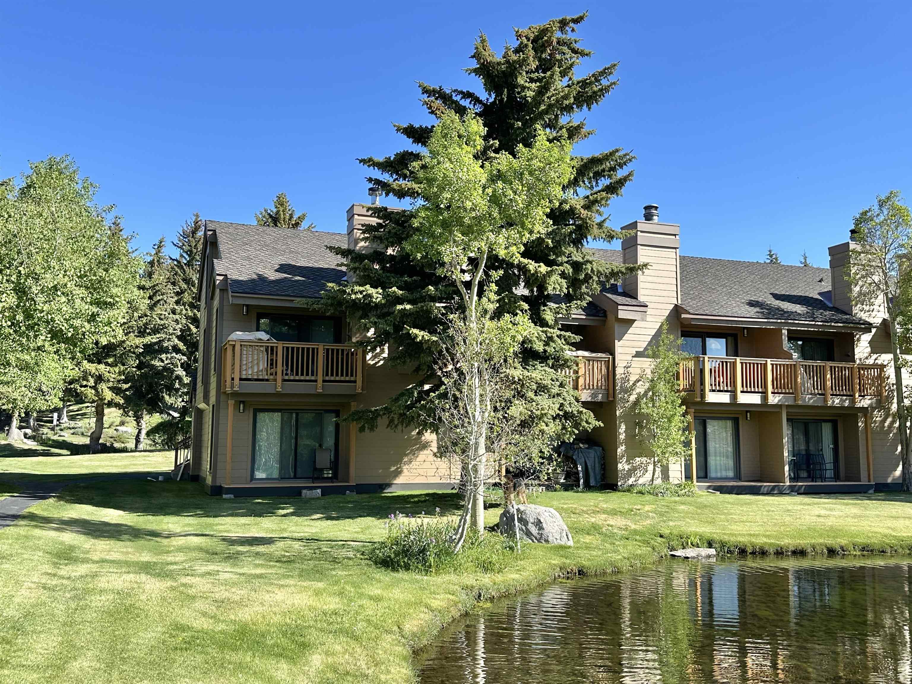 315 Fascination, Unit 315 Mammoth Lakes, CA 93546 - Photo 5 of 44 Two-story building featuring multiple balconies with wood railings, private patios with sliding glass doors, and a waterside location