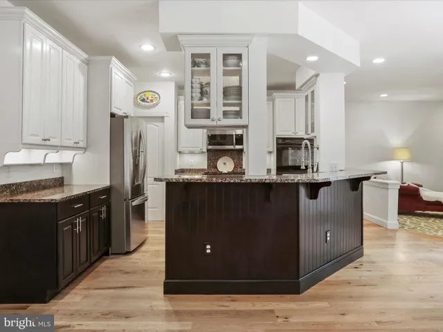 a kitchen with stainless steel appliances granite countertop a stove a sink dishwasher and a microwave oven with wooden cabinets