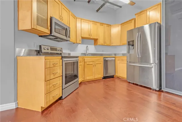 a kitchen with stainless steel appliances granite countertop a refrigerator a stove and a sink