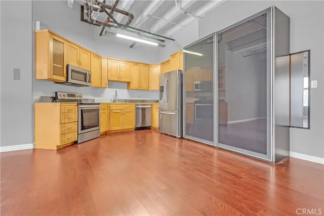 a large kitchen with stainless steel appliances granite countertop a refrigerator a stove and a wooden floors