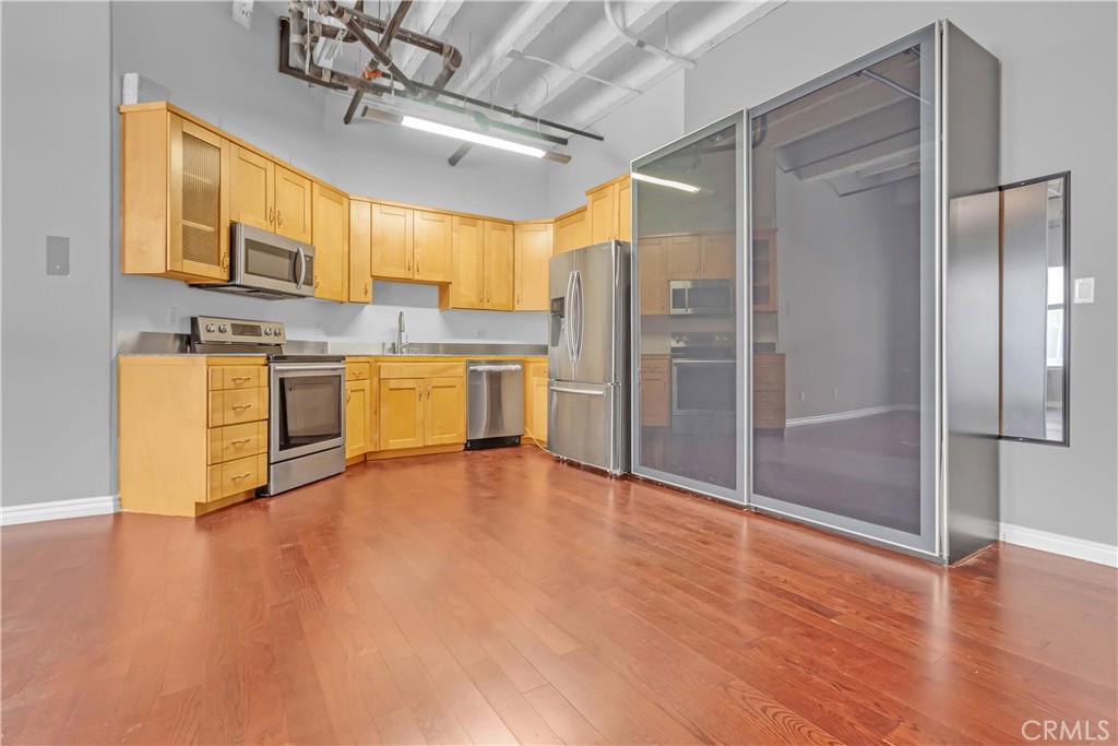 312 West 5th Street, Unit 1109 Los Angeles, CA 90013 - Photo 8 of 47 a large kitchen with stainless steel appliances granite countertop a refrigerator a stove and a wooden floors