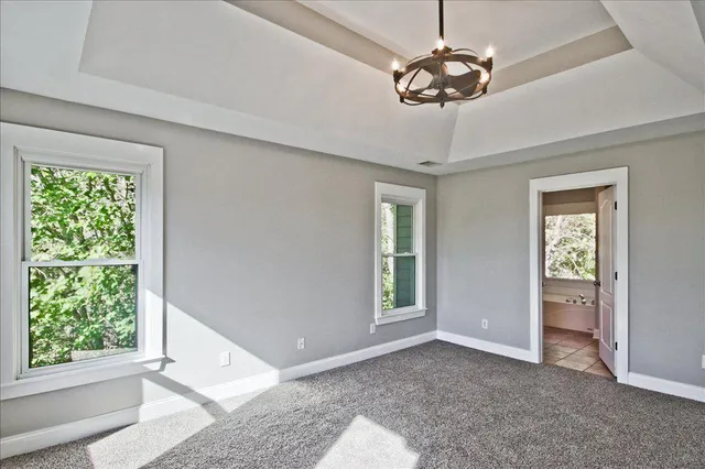 an empty room with windows and chandelier fan